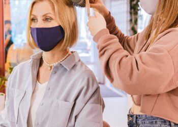 Mujer aplicando mascarilla hidratante en el cabello en un salón de belleza