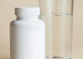Bote de suplemento de colágeno junto a un vaso de agua para la rutina diaria de cuidado