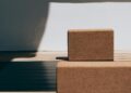 Esterillas de yoga enrolladas y bloques sobre suelo de madera para comparar grosor y material