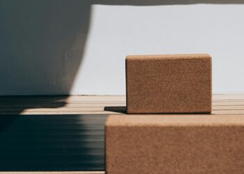 Esterillas de yoga enrolladas y bloques sobre suelo de madera para comparar grosor y material