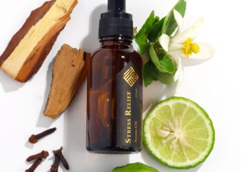 Aceite de romero para el pelo en frasco de vidrio junto a hierbas naturales
