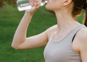 Mujer hidratándose con agua al aire libre para prevenir un golpe de calor en verano