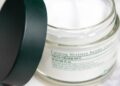 Crema reparadora sin perfume para piel sensible junto a una toalla de algodón