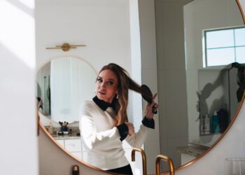 Mujer cepillando su melena larga frente al espejo para prevenir las puntas abiertas