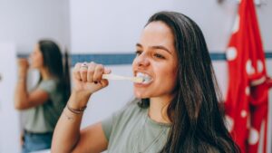 Mujer cepillándose los dientes con técnica suave para cuidar las encías inflamadas