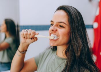 Mujer cepillándose los dientes con técnica suave para cuidar las encías inflamadas