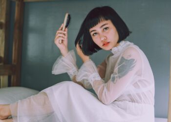 Mujer con melena corta sujetando un cepillo, ilustrando el cuidado del pelo fino y cómo darle volumen
