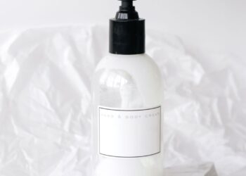 Frasco de aceite de almendras dulces sobre una superficie clara junto a productos de cuidado natural