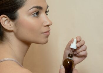 Mujer sosteniendo un frasco con cuentagotas de aceite de ricino para su rutina de cuidado
