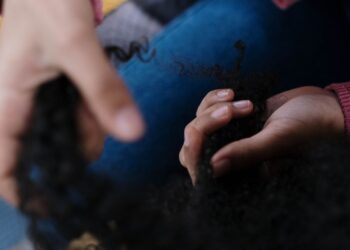 Manos definiendo mechones de pelo rizado durante una rutina de cuidado capilar