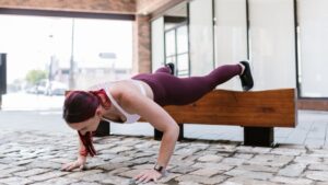 Mujer realizando flexiones inclinadas con las manos apoyadas en una superficie elevada al aire libre