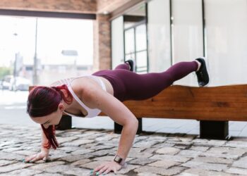 Mujer realizando flexiones inclinadas con las manos apoyadas en una superficie elevada al aire libre