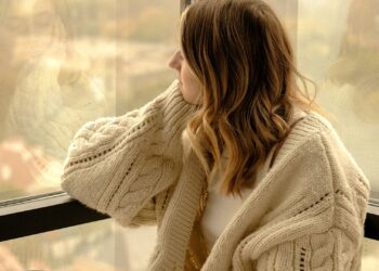 Mujer con una taza de té junto a la ventana afrontando el bajón de otoño