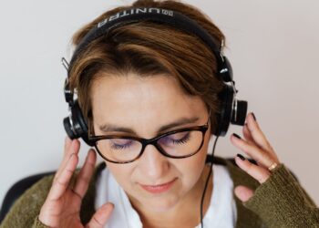Mujer con auriculares escuchando música a volumen moderado para cuidar su salud auditiva