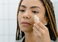 Mujer aplicando crema frente al espejo como parte de su rutina de cuidado personal en otoño