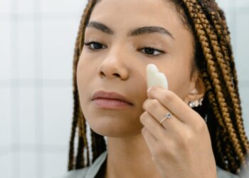 Mujer aplicando crema frente al espejo como parte de su rutina de cuidado personal en otoño
