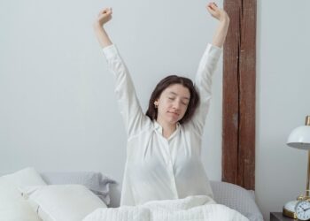 Mujer despertándose en la cama con luz natural, ejemplo de cómo levantarse temprano sin sufrir