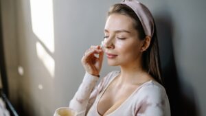 Mujer aplicando crema hidratante en el rostro para cuidar la piel seca