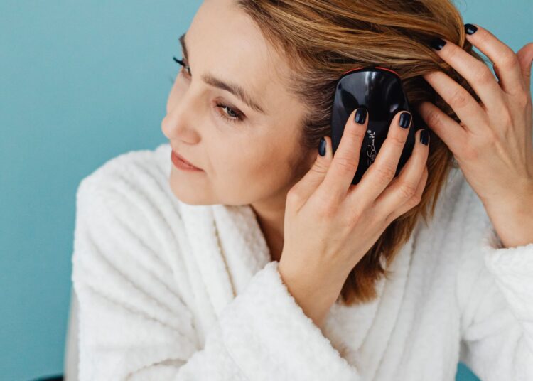 Mujer cepillándose el pelo frente al espejo con uno de los mejores cepillos para el pelo